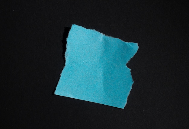 Trozo de papel azul con un trozo de papel rasgado en el medio