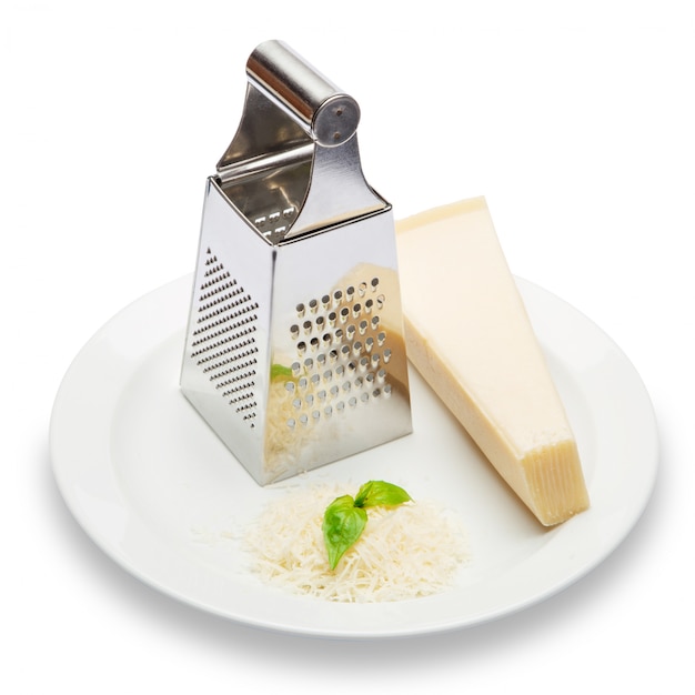 Un trozo de parmesano y queso rallado en mesa blanca