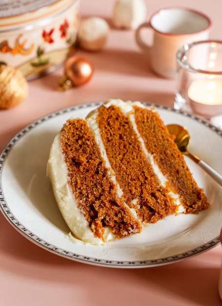 Trozo de pastel de capas de zanahoria en un plato blanco con fondo estacional de Navidad