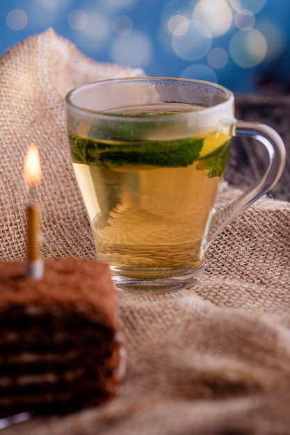 Foto un trozo de pastel de fresa dulce con una taza de té de limón y una hoja de menta sobre una arpillera en la mesa