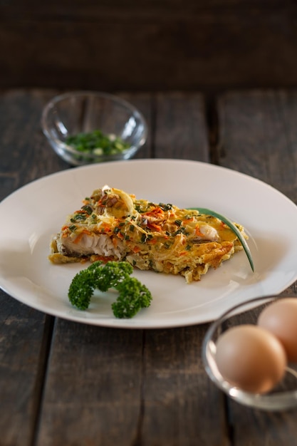 Un trozo de pastel hecho con huevos de pescado, cebollas y zanahorias Placa blanca tablones de madera