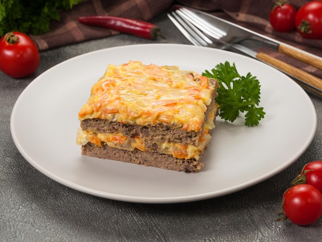 Un trozo de pastel de hígado decorado con verduras en un plato gris