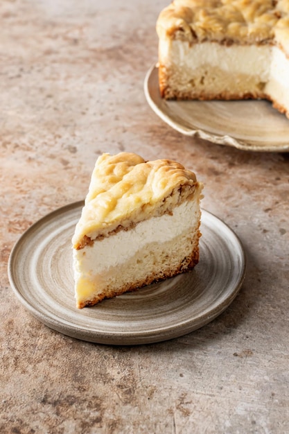 Un trozo de pastel de requesón casero o tarta de queso en un plato de cerámica sobre fondo marrón