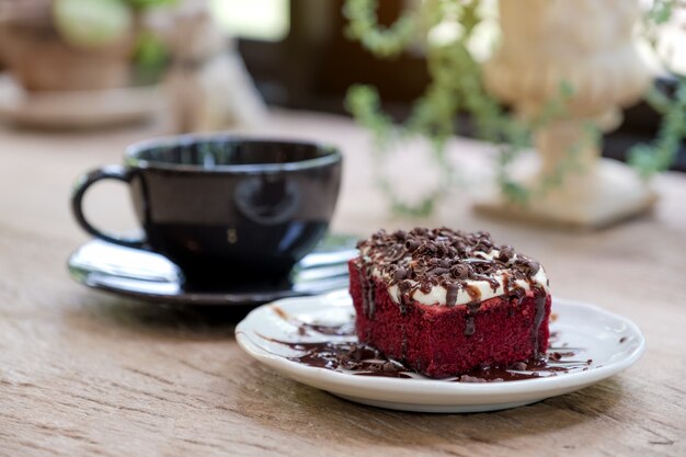 Un trozo de pastel de terciopelo rojo con una taza de café.