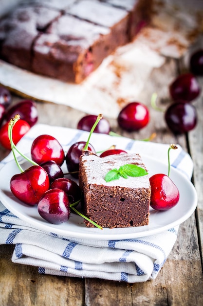 Un trozo de postre de brownie de chocolate casero con una cereza en un plato