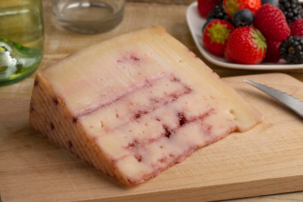 Trozo de queso de cabra español con almíbar de frutos rojos inyectado en una tabla para cortar