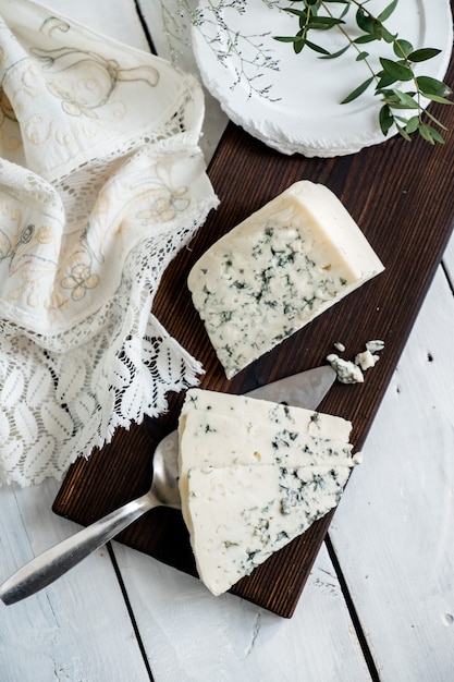 Foto un trozo de queso dor azul sobre una tabla de quesos con cuchillos delicadeza quesos azules.