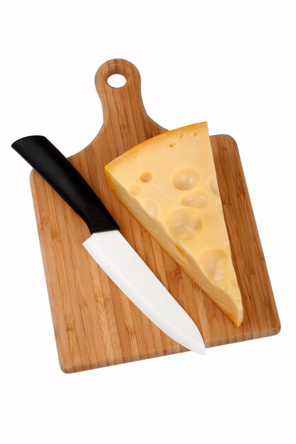 Trozo de queso en placa de cocina y cuchillo de cerámica sobre fondo blanco.