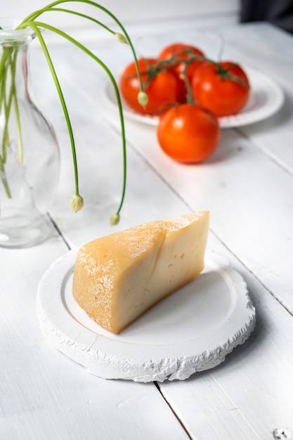 Trozo de queso con tomates sobre una tabla de madera, muestras de queso, queso con un corte