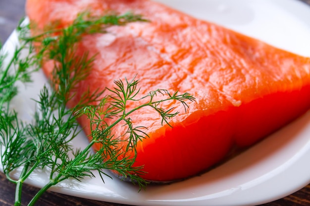 Un trozo de salmón salvaje ligeramente salado con eneldo fresco sobre una mesa de madera