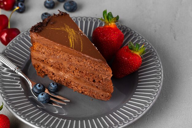 Trozo de tarta de chocolate servido con frutos rojos frescos. Postre sabroso