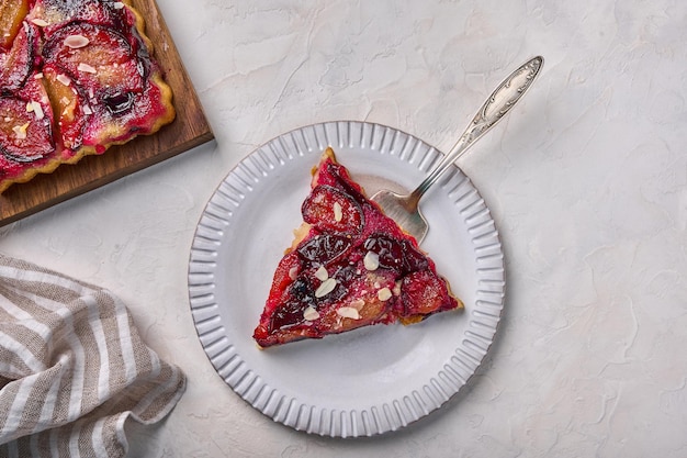 Trozo de tarta de ciruela en un plato ligero con el omóplato junto a la servilleta de tarta plana