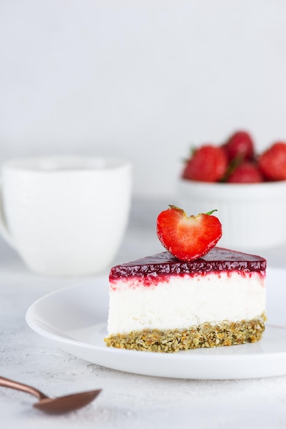 Un trozo de tarta de coliflor mousse cruda con fresas sobre un fondo claro