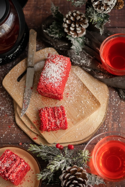 Trozo de tarta de fresa y té de frutos rojos, con adornos de invierno