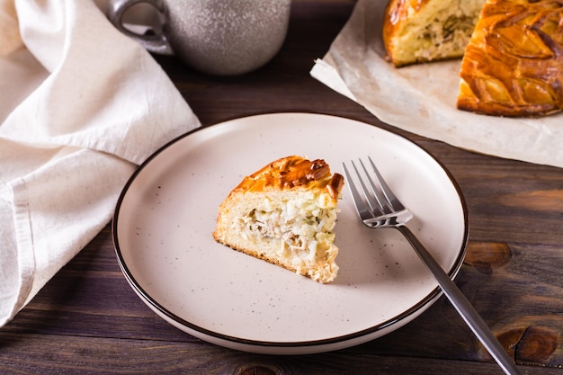 Un trozo de tarta kurnik con pollo, patatas y arroz en un plato Pasteles caseros