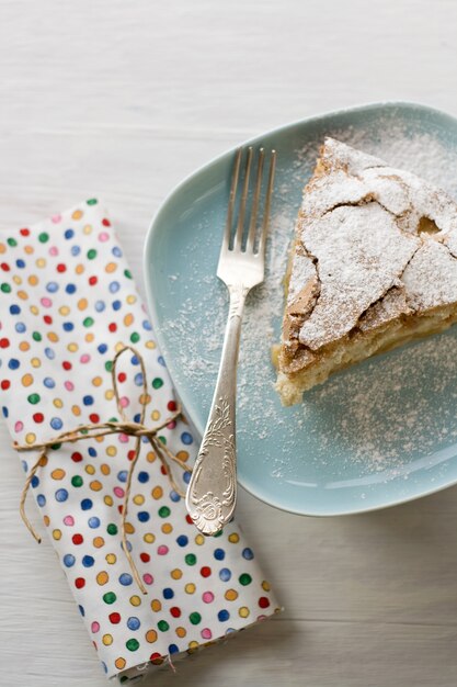 Un trozo de tarta de manzana sobre la placa gris, tenedor sobre un color