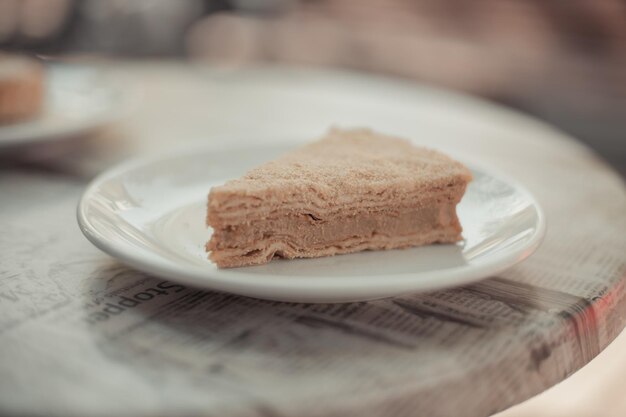 Un trozo de tarta napoleón casera con crema sobre una mesa en un restaurante de la calle. Comida sabrosa por la mañana