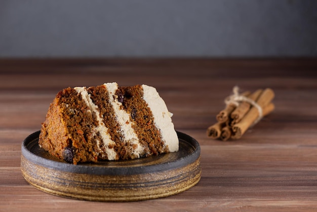 Un trozo de tarta de zanahoria con crema de coco, nueces y especias sobre una mesa de madera