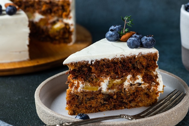 Trozo de tarta de zanahoria con nueces y arándanos sobre fondo de madera oscura. Comida local. Pastel americano tradicional. Pastel para el día de acción de gracias. Pastel de Navidad.