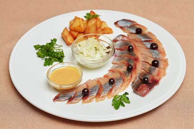 Trozos de arenque con patatas y verduras en un plato