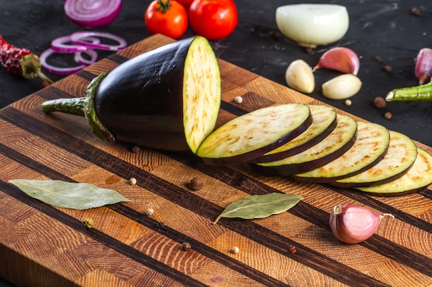 Trozos de berenjenas en rodajas sobre una tabla para cortar. Preparación de un plato de berenjenas y verduras frescas. Plato de berenjenas