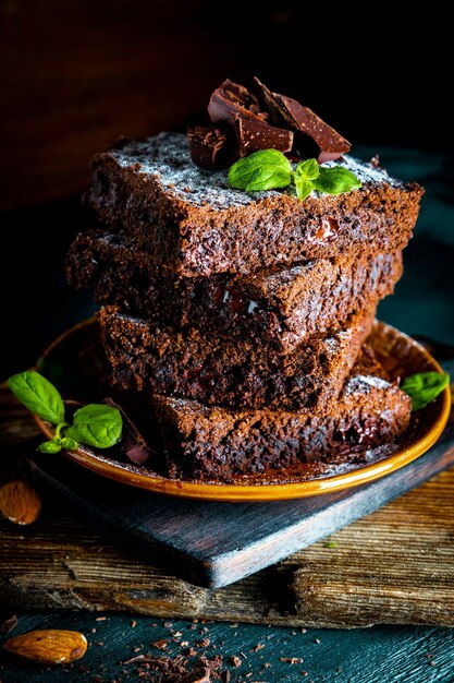 Trozos de brownie de chocolate casero aderezado con hojas de menta, foto vertical. Foto de alta calidad