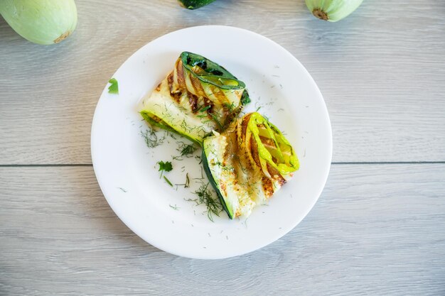 Trozos de calabacín a la parrilla con salsa de ajo en un plato blanco