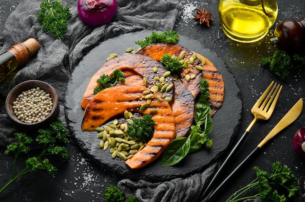 Trozos de calabaza al horno con semillas de calabaza en un plato de piedra negra Menú de otoño Dieta Vista superior Espacio libre para texto