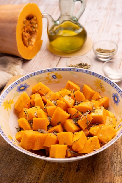 Trozos de calabaza en dados en un bol con especias y aceite de oliva