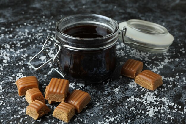 Trozos de caramelo salado y salsa sobre fondo negro ahumado