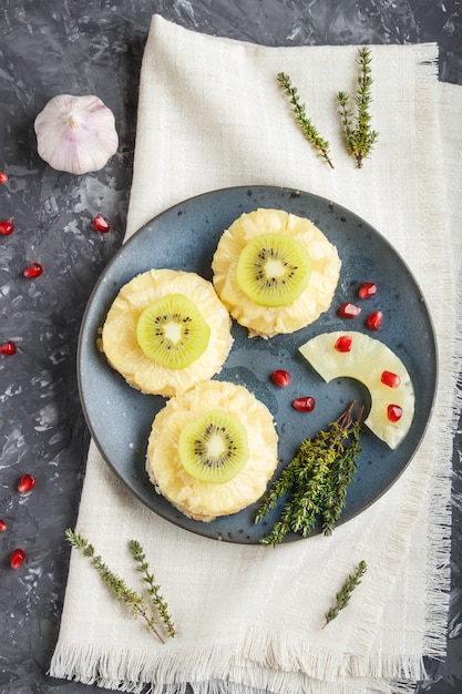 Trozos de carne de cerdo al horno con queso de piña y kiwi sobre fondo negro