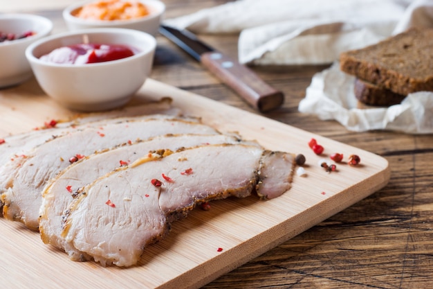 Trozos de carne de cerdo hervida ahumada sobre una tabla de madera rústica