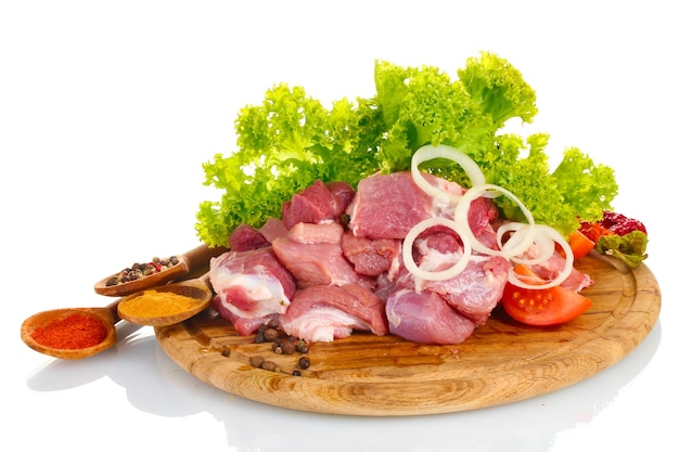 Trozos de carne cruda y verduras sobre tablero de madera aislado en blanco