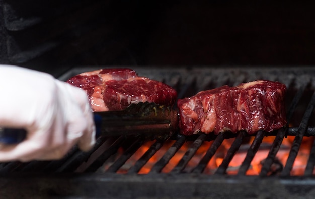 Trozos de carne de res a la parrilla y la mano de un hombre.