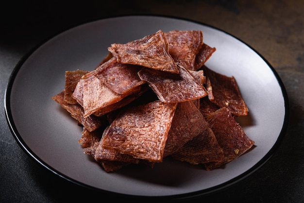 Trozos de carne seca a la parrilla chips de pollo de cerdo de res se encuentran en un plato gris Snack para cerveza