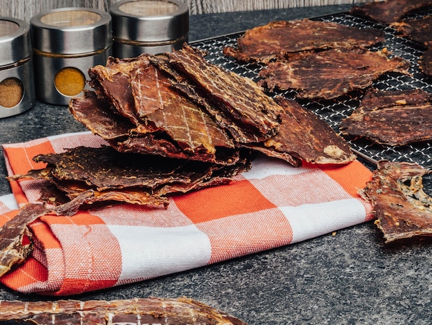 Foto trozos de carne seca rebanadas deshidratadas en especias en la toalla de cocina