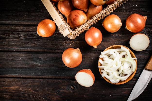 Trozos de cebolla en un plato y cebollas enteras en una caja