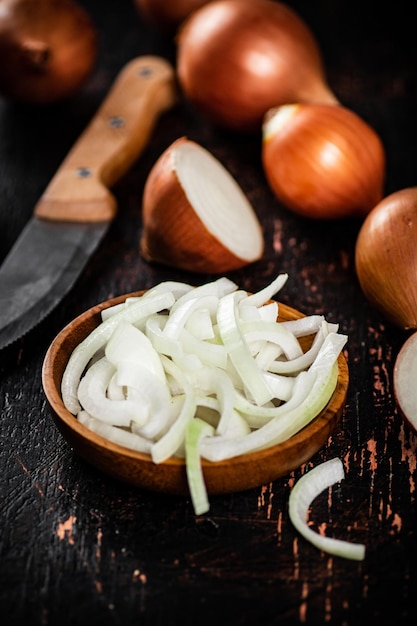 Foto trozos de cebolla en un plato de madera sobre la mesa