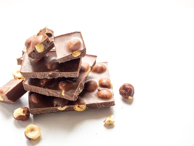 Trozos de chocolate con avellanas sobre un fondo blanco.