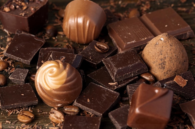 Trozos de chocolate y dulces en la mesa de madera oscura.