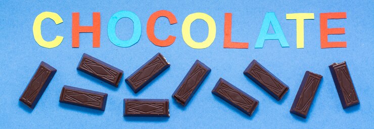 Foto trozos de chocolate y la inscripción chocolate sobre un fondo azul.