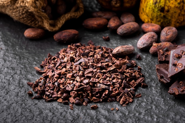 Foto trozos de chocolate negro triturados y granos de cacao, vista superior