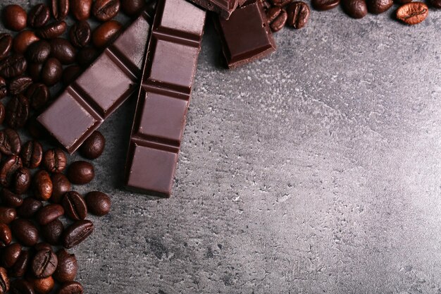 Trozos de chocolate oscuro y granos de café sobre fondo gris oscuro