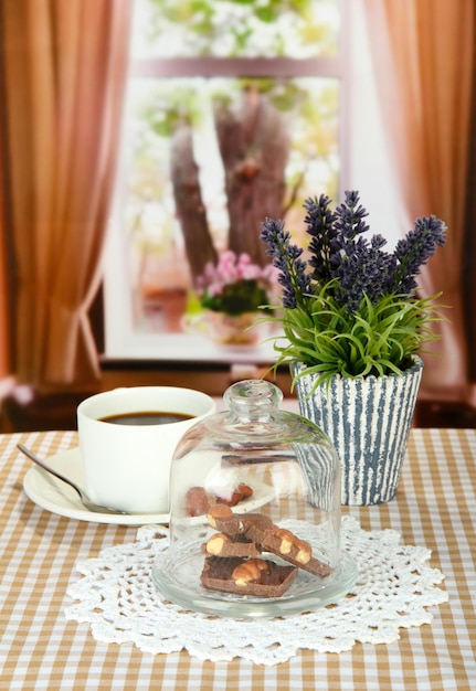 Trozos de chocolate bajo la tapa de vidrio y bebida caliente sobre fondo brillante