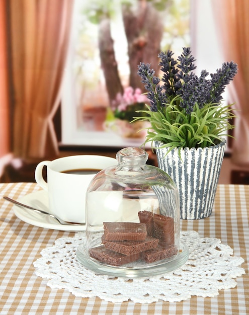 Trozos de chocolate bajo la tapa de vidrio y bebida caliente sobre fondo brillante