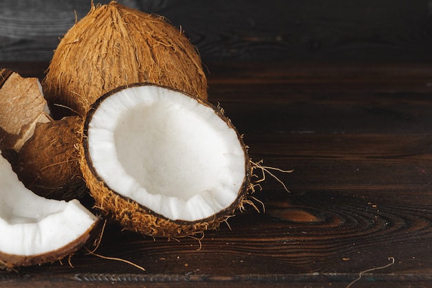 Trozos de coco agrietados sobre fondo de madera oscura