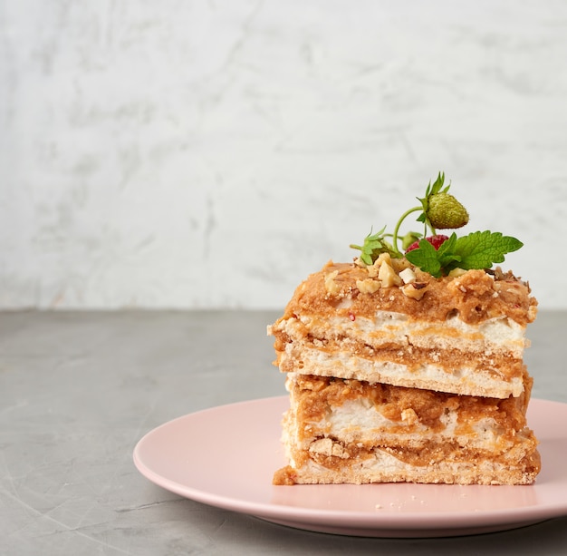 Trozos cuadrados de pastel de merengue con crema en un plato rosa