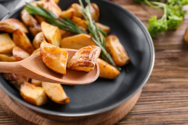 Trozos de deliciosa patata al horno con romero en cuchara sobre pan closeup