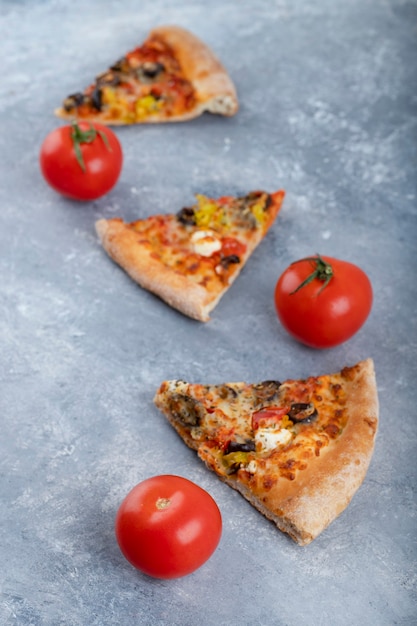 Trozos de deliciosa pizza con tomates rojos frescos colocados sobre un fondo de piedra.