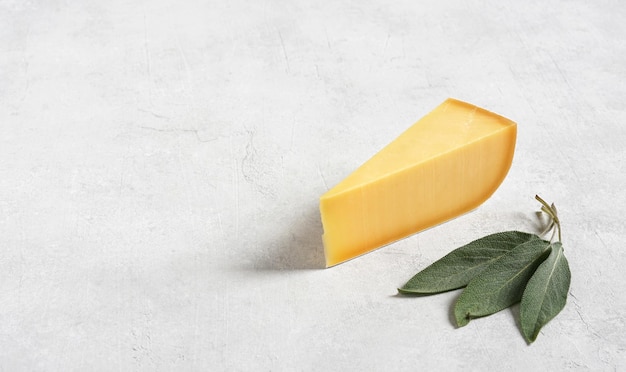 Trozos de delicioso queso parmesano y hojas de salvia en un espacio de fondo blanco para texto